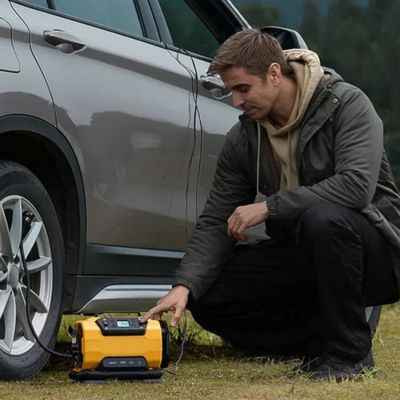 gonfleur pneu voiture homme accroupi devant voiture
